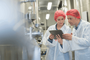 Benefits of Quality Control. Factory workers reviewing product on a tablet